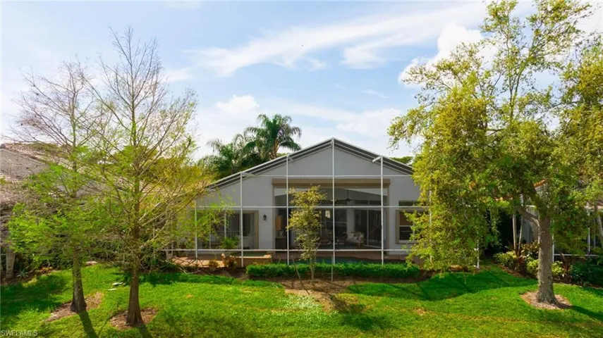 Rear view of property with screen enclosure and a yard