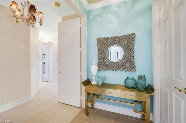 Hall with tile patterned flooring, a notable chandelier, crown molding