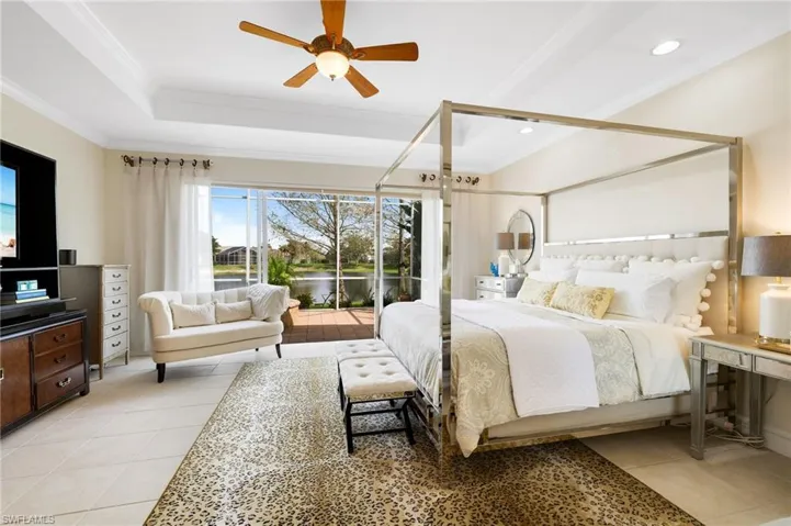 Bedroom with light tile patterned floors, a ceiling fan, access to outside, crown molding, and a tray ceiling