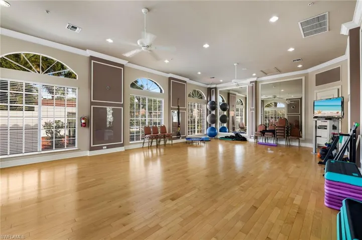 Exercise area featuring light wood finished floors, visible vents, a wealth of natural light, and crown molding