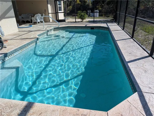 View of swimming pool featuring a lanai and a patio area
