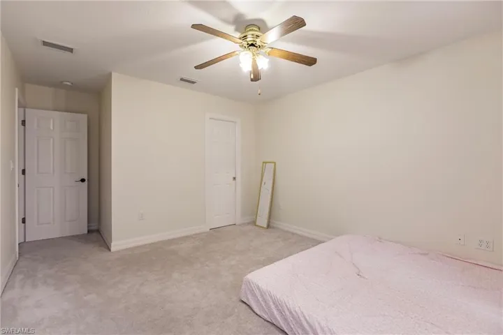 Bedroom with ceiling fan and light colored carpet