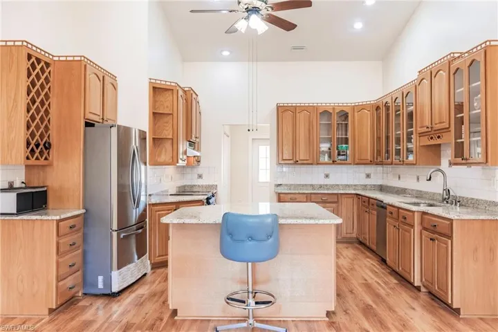 Kitchen featuring light hardwood / wood-style flooring, a center island, a high ceiling, appliances with stainless steel finishes, and sink