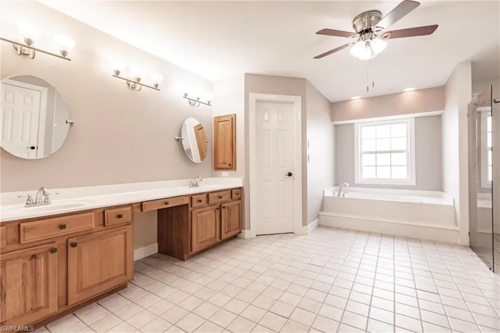 Bathroom featuring ceiling fan, tile patterned floors, plus walk in shower, and vanity