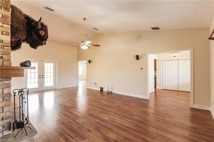Unfurnished living room with french doors, high vaulted ceiling, ceiling fan, and dark wood-type flooring