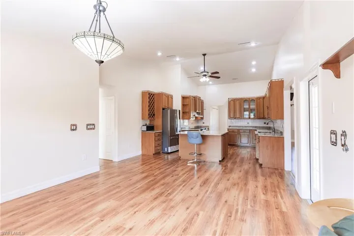 Kitchen with sink, decorative light fixtures, light wood-type flooring, stainless steel fridge, and a kitchen island