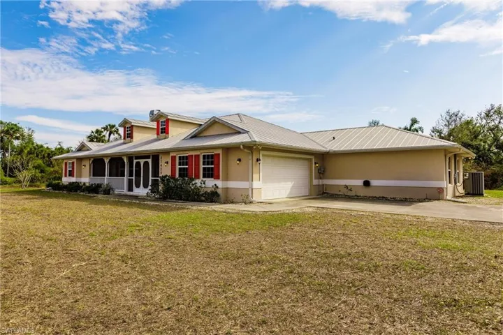 Ranch-style home with a front yard, central AC unit, and a garage