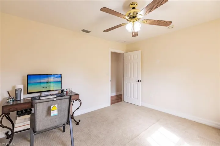 Home office featuring ceiling fan and light carpet