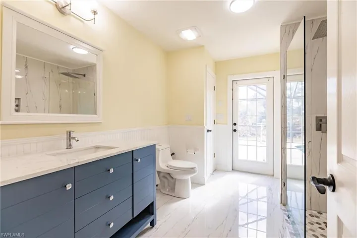 Bathroom featuring a tile shower, vanity, and toilet