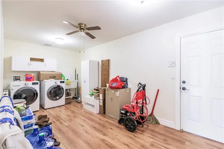Clothes washing area with sink, cabinets, ceiling fan, light wood-type flooring, and washer and clothes dryer