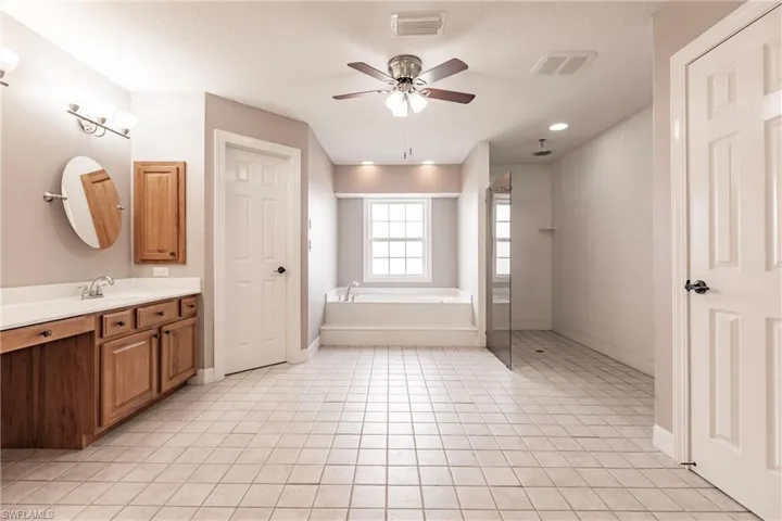 Bathroom featuring ceiling fan, separate shower and tub, tile patterned flooring, and vanity