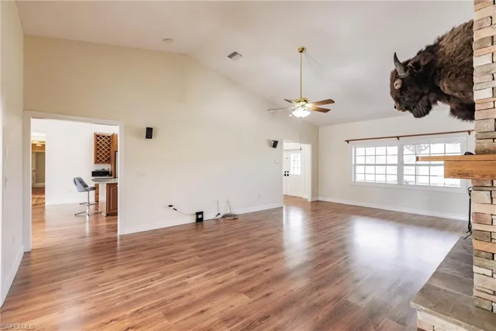 Unfurnished living room featuring ceiling fan, lofted ceiling, and dark hardwood / wood-style floors