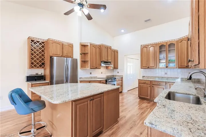 Kitchen featuring stainless steel appliances, sink, a kitchen island, a kitchen bar, and high vaulted ceiling