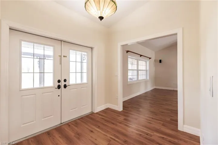 Foyer entrance featuring lofted ceiling, dark wood-type flooring, french doors, and a wealth of natural light