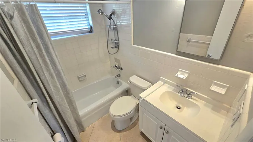 Bathroom #2  featuring a bathtub with shower fixture, white subway tile surround, white vanity with integrated sink, and an unframed mirror