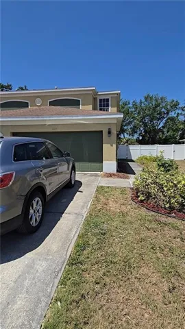 View of side of home with stucco siding, fence, and driveway