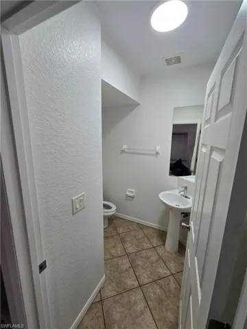 Bathroom featuring visible vents, toilet, a sink, baseboards, and tile patterned floors