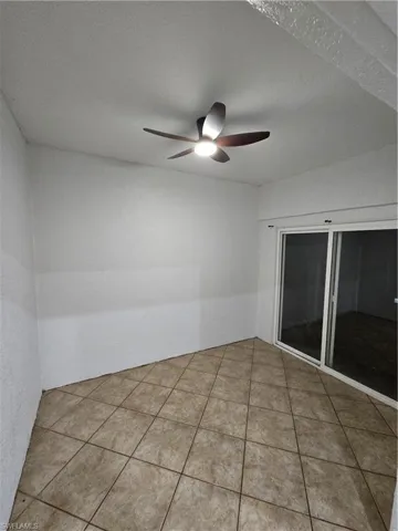 Tiled spare room featuring a ceiling fan