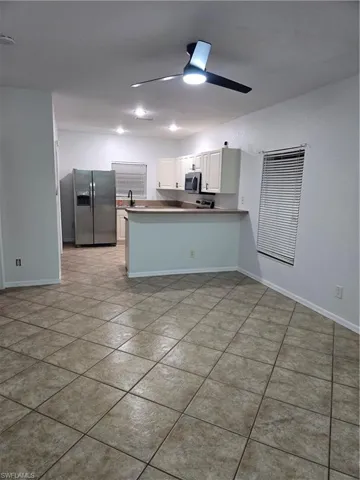Kitchen featuring ceiling fan, a peninsula, a sink, white cabinetry, and fridge