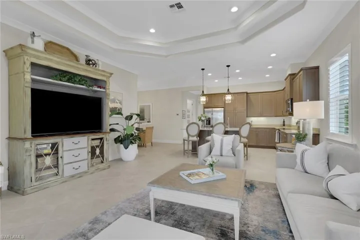 Living area with recessed lighting, a tray ceiling, light tile patterned floors, and ornamental molding