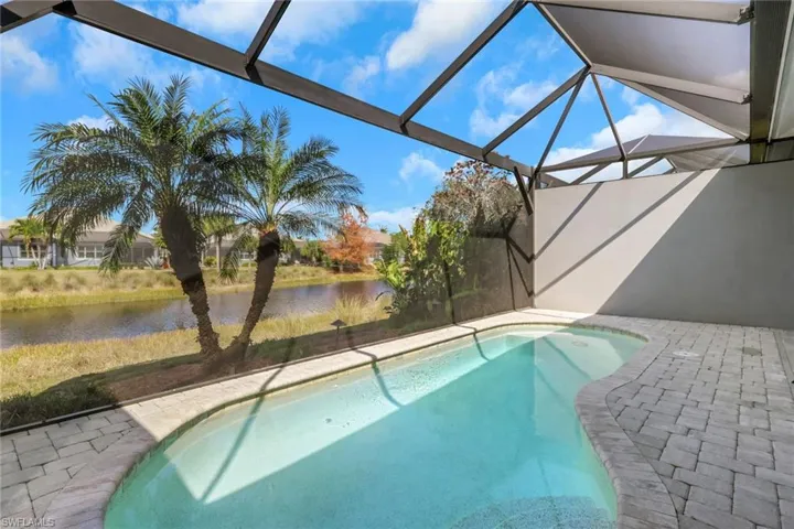 Outdoor pool featuring a sunroom, a patio area, a lanai, and a water view