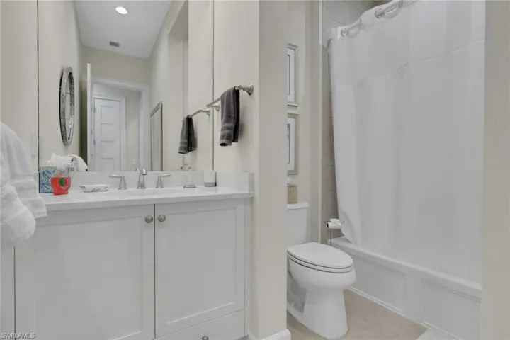 Full bathroom with shower / tub combo, vanity, and light tile patterned flooring