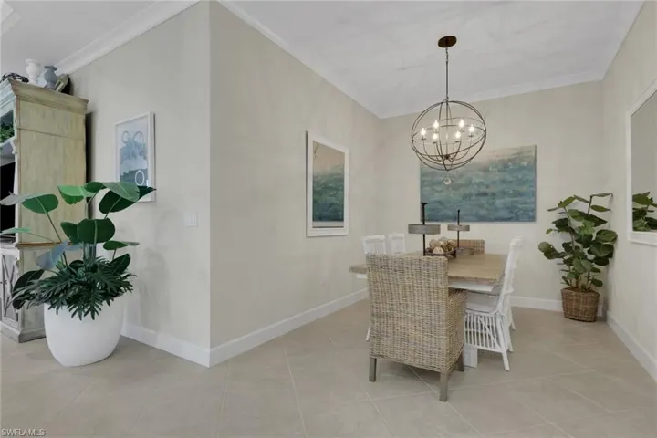 Dining room featuring ornamental molding, a chandelier, and light tile patterned floors