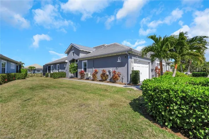 View of front of property featuring stucco siding, a front lawn, a garage, and a sunroom