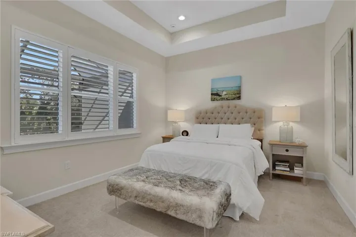 Bedroom featuring a raised ceiling, light carpet, and recessed lighting