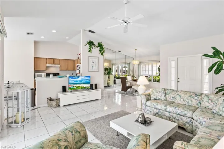 Living room with high vaulted ceiling, light tile flooring, and ceiling fan