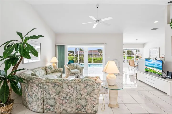 Living room with vaulted ceiling, ceiling fan, and light tile floors