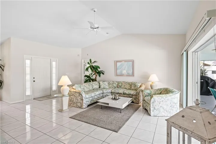 Tiled living room featuring ceiling fan and vaulted ceiling