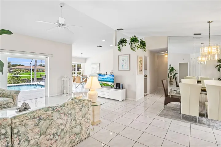 Tiled living room with ceiling fan with notable chandelier