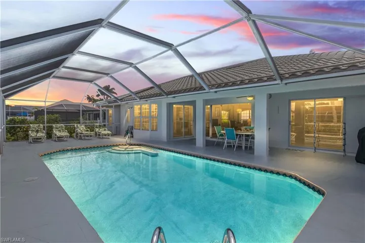 Pool at dusk featuring a patio and glass enclosure
