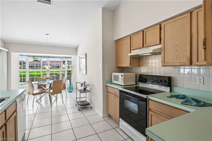 Kitchen with light tile flooring, white appliances, and backsplash
