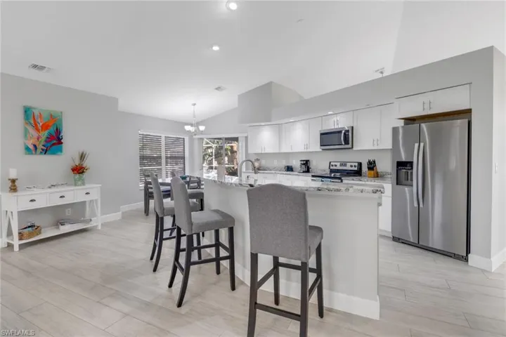 Kitchen featuring an island with sink, decorative light fixtures, light hardwood / wood-style floors, white cabinetry, and stainless steel appliances