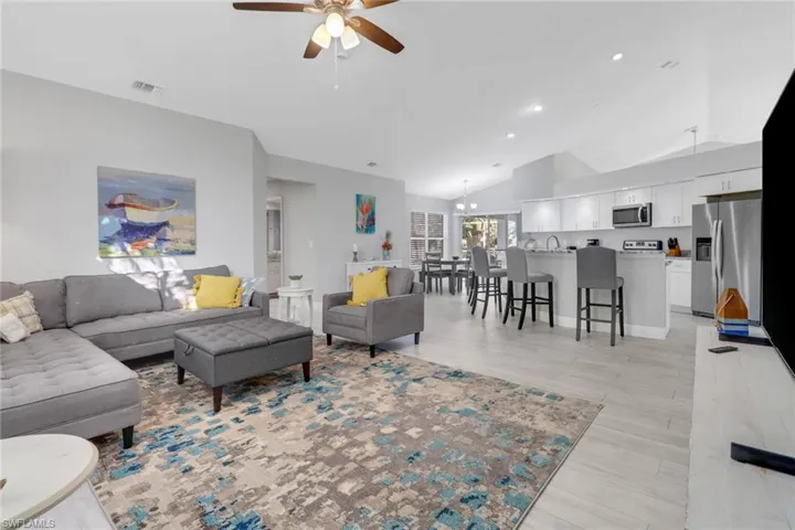 Living room featuring ceiling fan with notable chandelier, light hardwood / wood-style floors, lofted ceiling, and sink