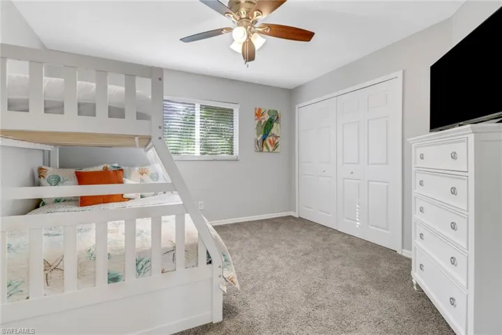 Carpeted bedroom featuring ceiling fan and a closet