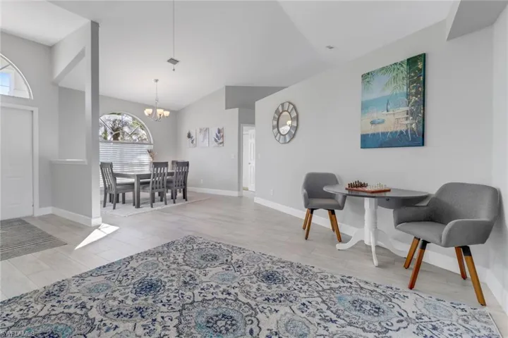 Living room with a chandelier, lofted ceiling, and light wood-type flooring