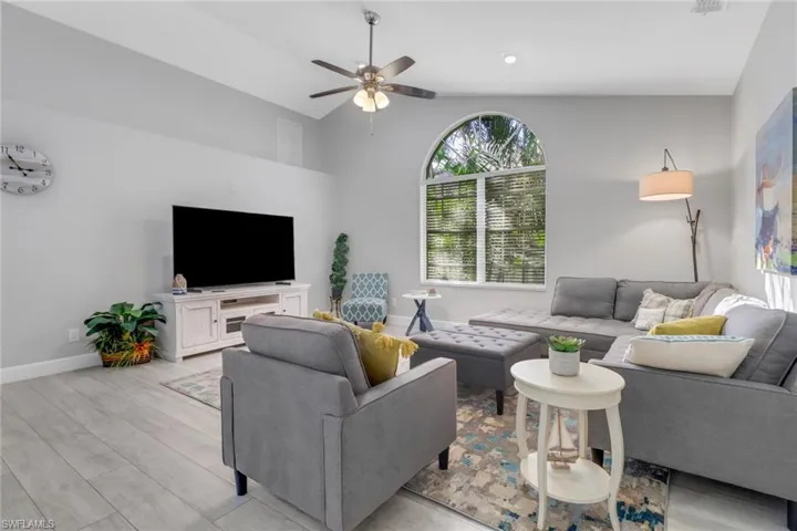 Living room with light wood-type flooring, vaulted ceiling, and ceiling fan