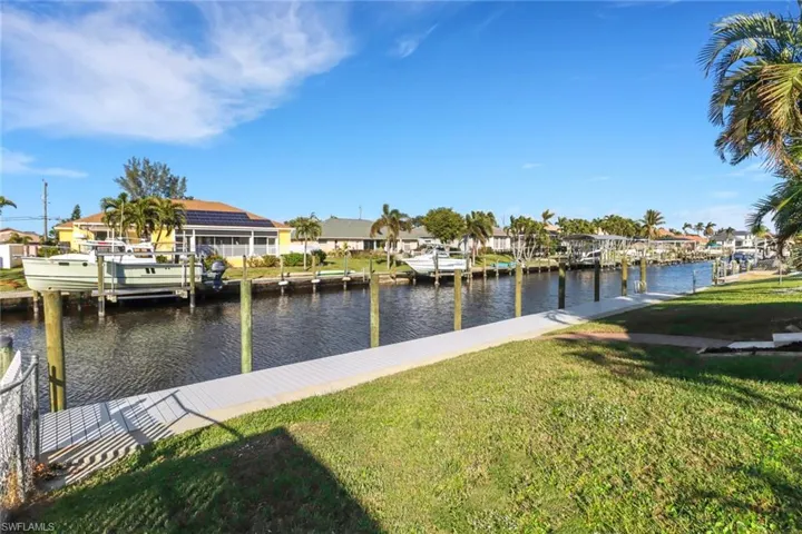 View of dock with a yard and a water view