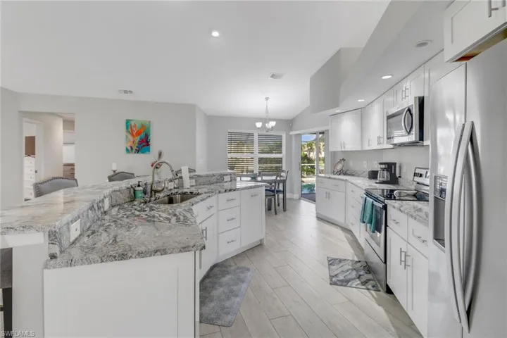 Kitchen featuring white cabinetry, sink, a large island with sink, light hardwood / wood-style floors, and appliances with stainless steel finishes
