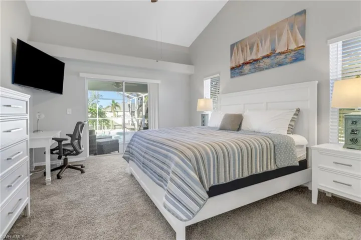 Bedroom with access to outside, light carpet, ceiling fan, and vaulted ceiling