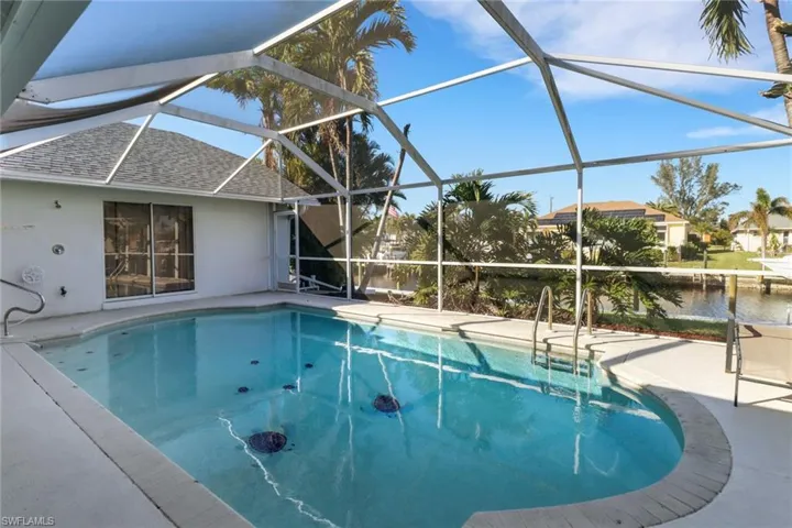 View of pool with a patio, a water view, and a lanai