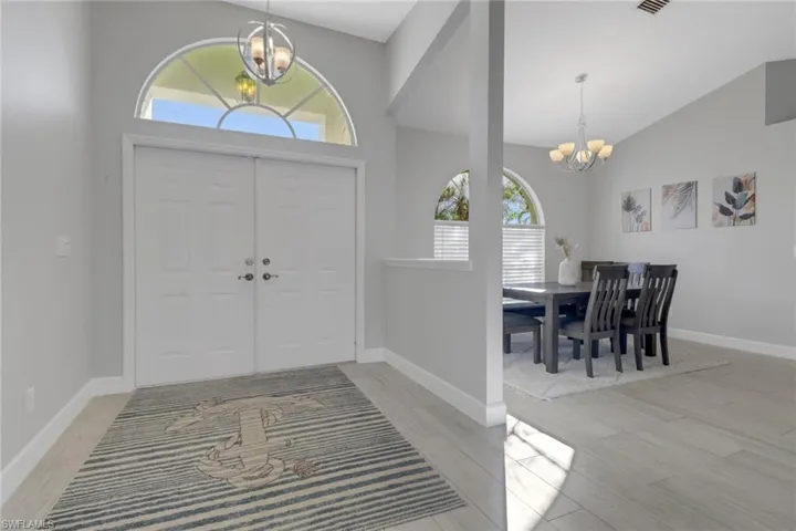 Entryway featuring a notable chandelier, plenty of natural light, and high vaulted ceiling