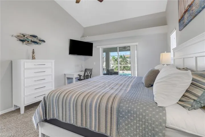 Carpeted bedroom featuring access to exterior, ceiling fan, and vaulted ceiling