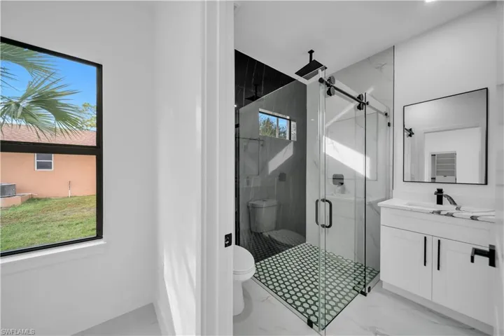 Full bath featuring vanity, a marble finish shower, and light marble finish floors