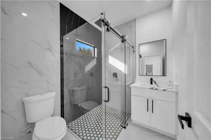 Bathroom with vanity and a marble finish shower