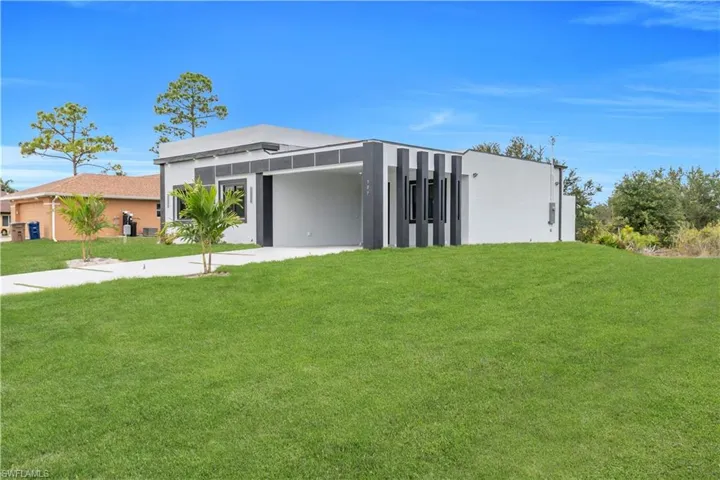 Modern home featuring a front lawn, concrete driveway, an attached carport, and stucco siding