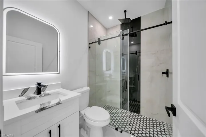 Bathroom with vanity, a marble finish shower, and recessed lighting